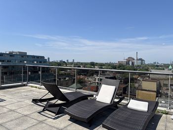 Three lounge chairs are on a rooftop terrace.